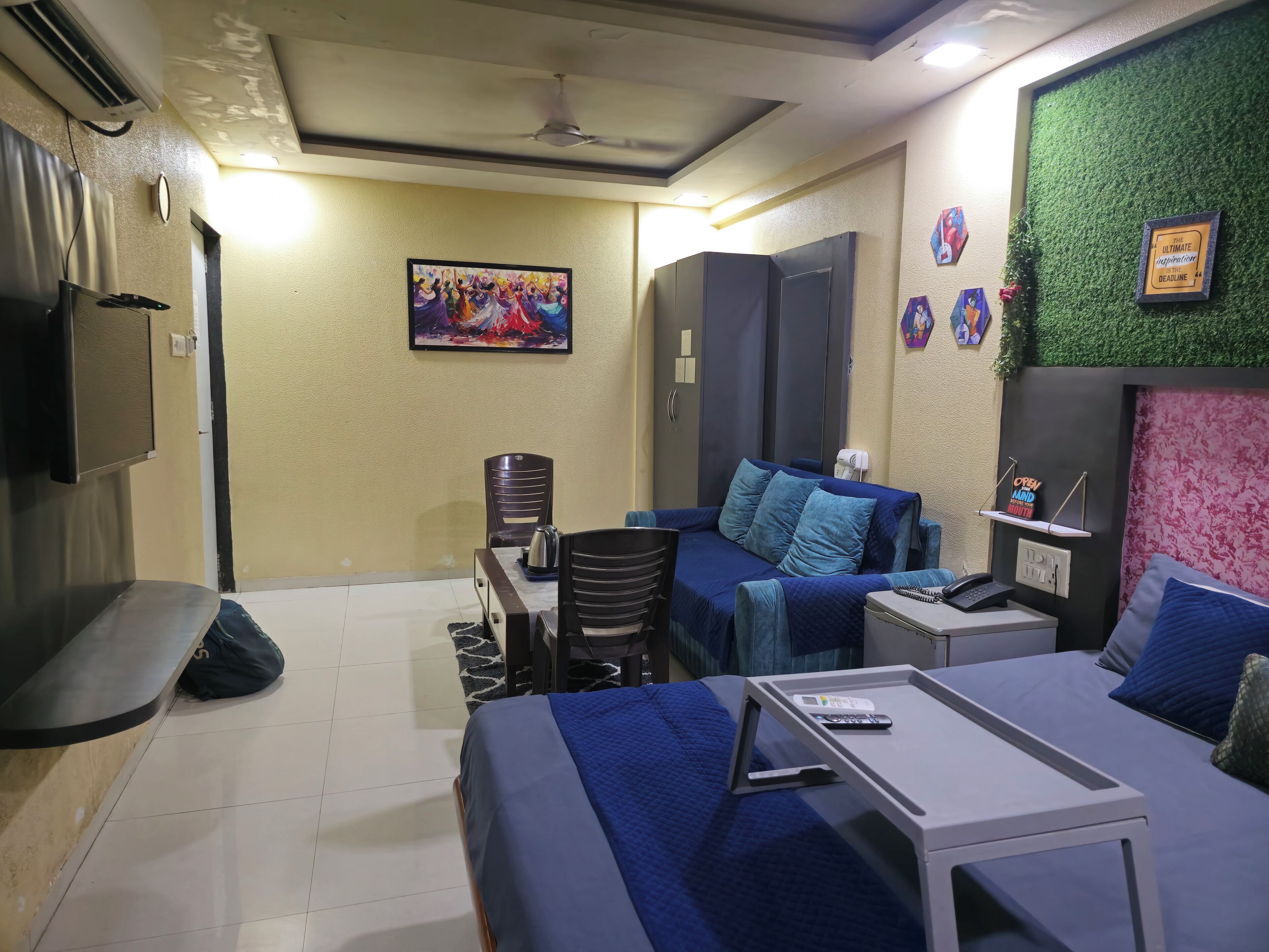 A compact hotel room with a bed, a small table, a sofa, and a TV.