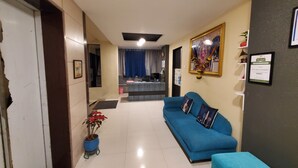 A hotel lobby with a blue sofa, a reception desk, and a framed certificate on the wall. - hotel mari aai residency (Panvel)