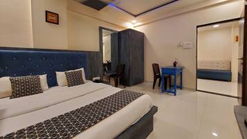 A hotel room with a large bed, a desk, a chair, and a sofa.
