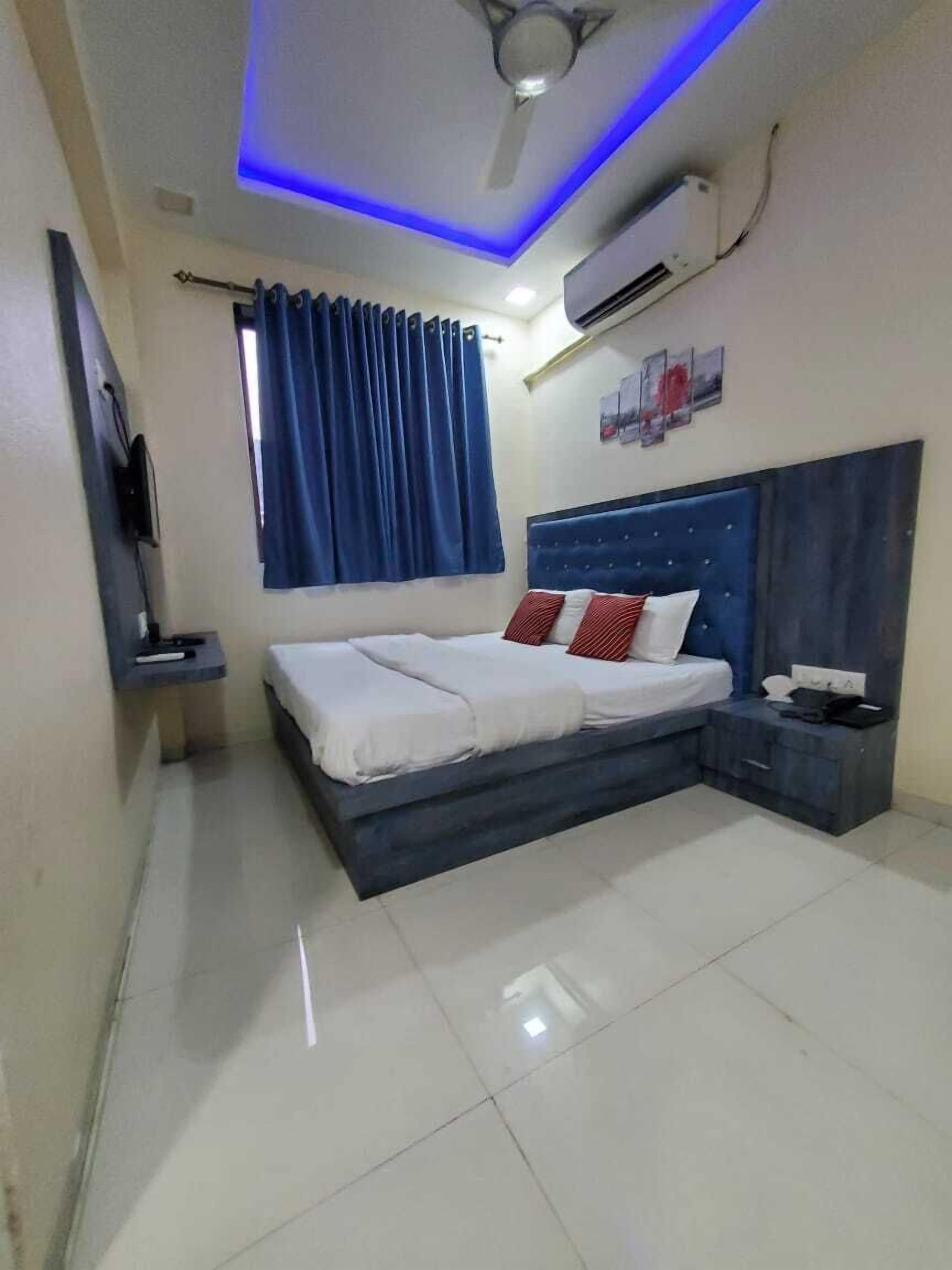 Een slaapkamer met een bed, nachtkastje, plafondventilator en een wandairconditioner.