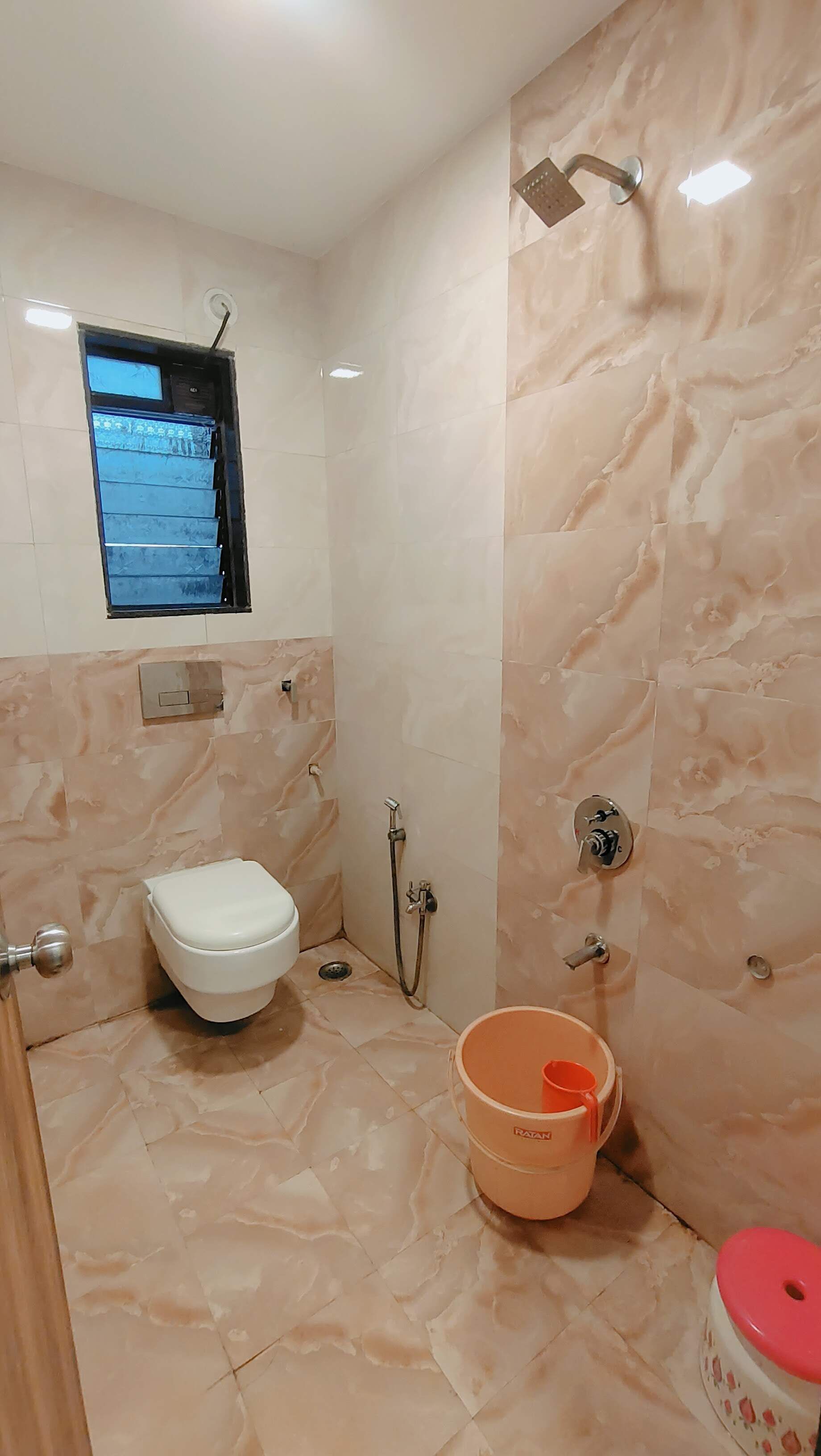 A bathroom with a toilet, a shower, and a bucket.