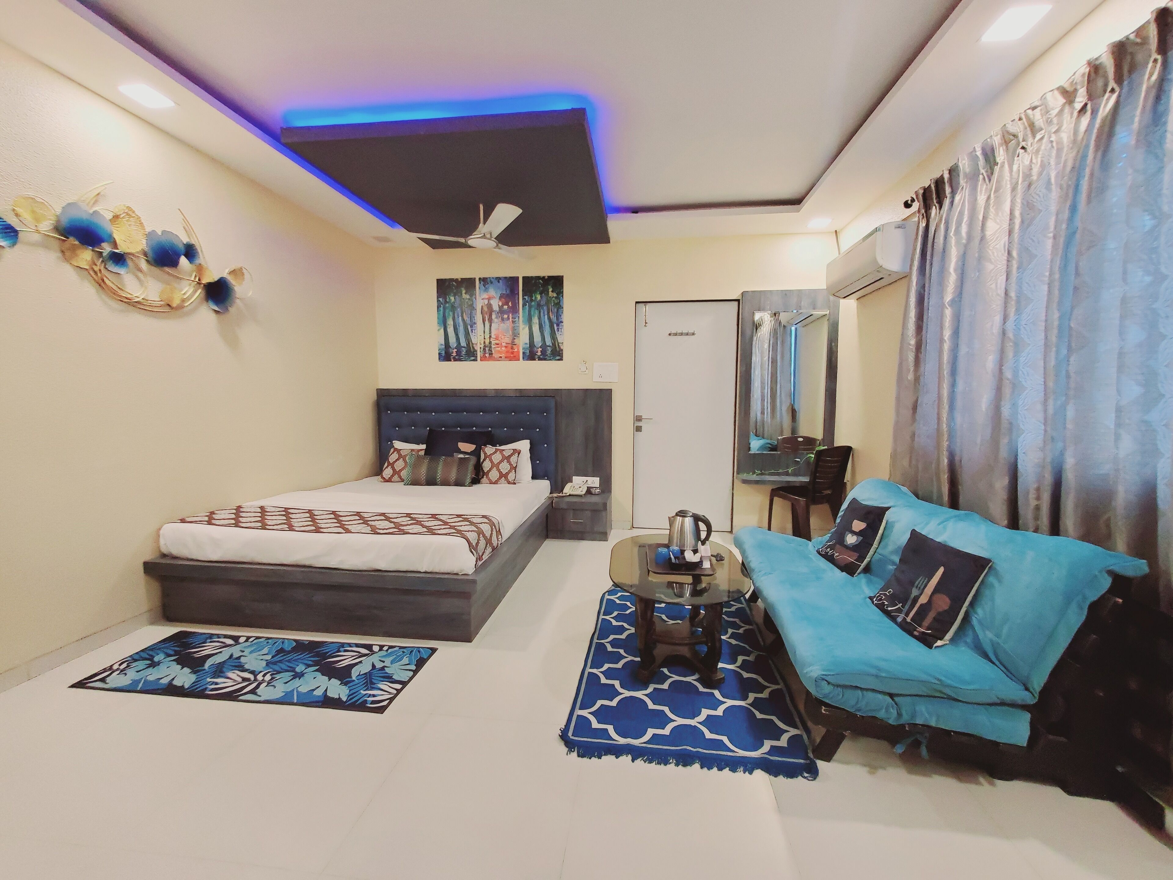 A bedroom with a bed, a sofa, a coffee table, and a ceiling fan.