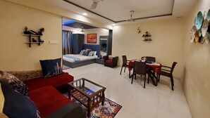 A modern living room with a sofa, coffee table, and dining area. - hotel mari aai residency (Panvel)