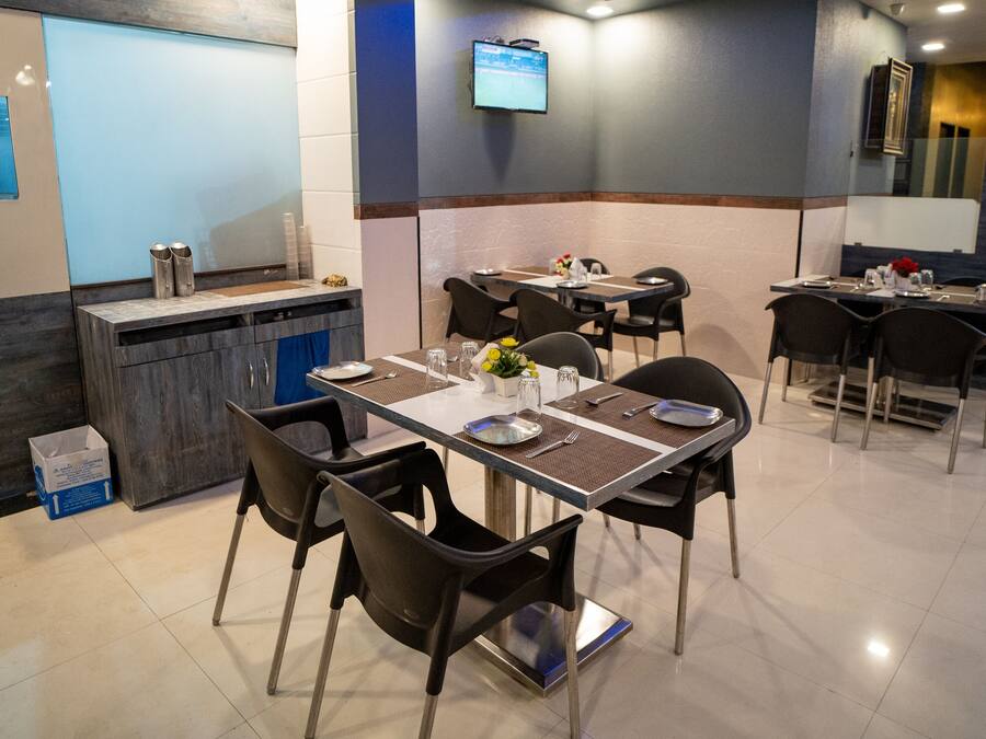 Un restaurante con mesas dispuestas para comer, una barra y un televisor montado en la pared.