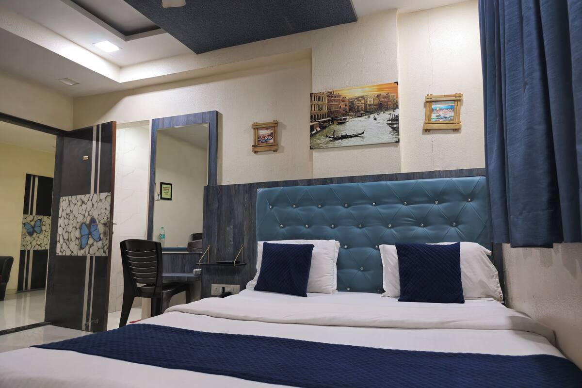 Een hotelkamer met een groot bed, een bureau, een stoel, een spiegel en kunstwerken aan de muur.