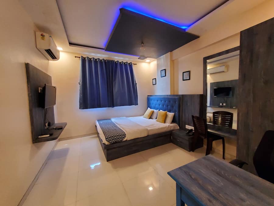 Un dormitorio moderno con cama, escritorio, silla, televisor y una lámpara en el techo.