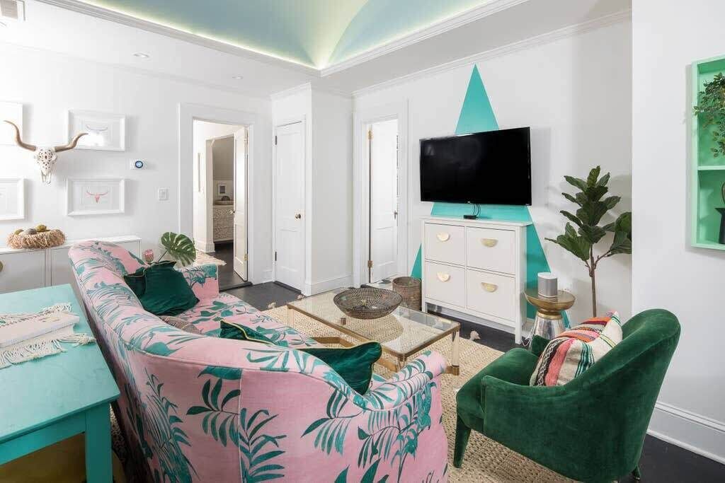 A living room with a sofa, a green armchair, a coffee table, and a television on a white cabinet.