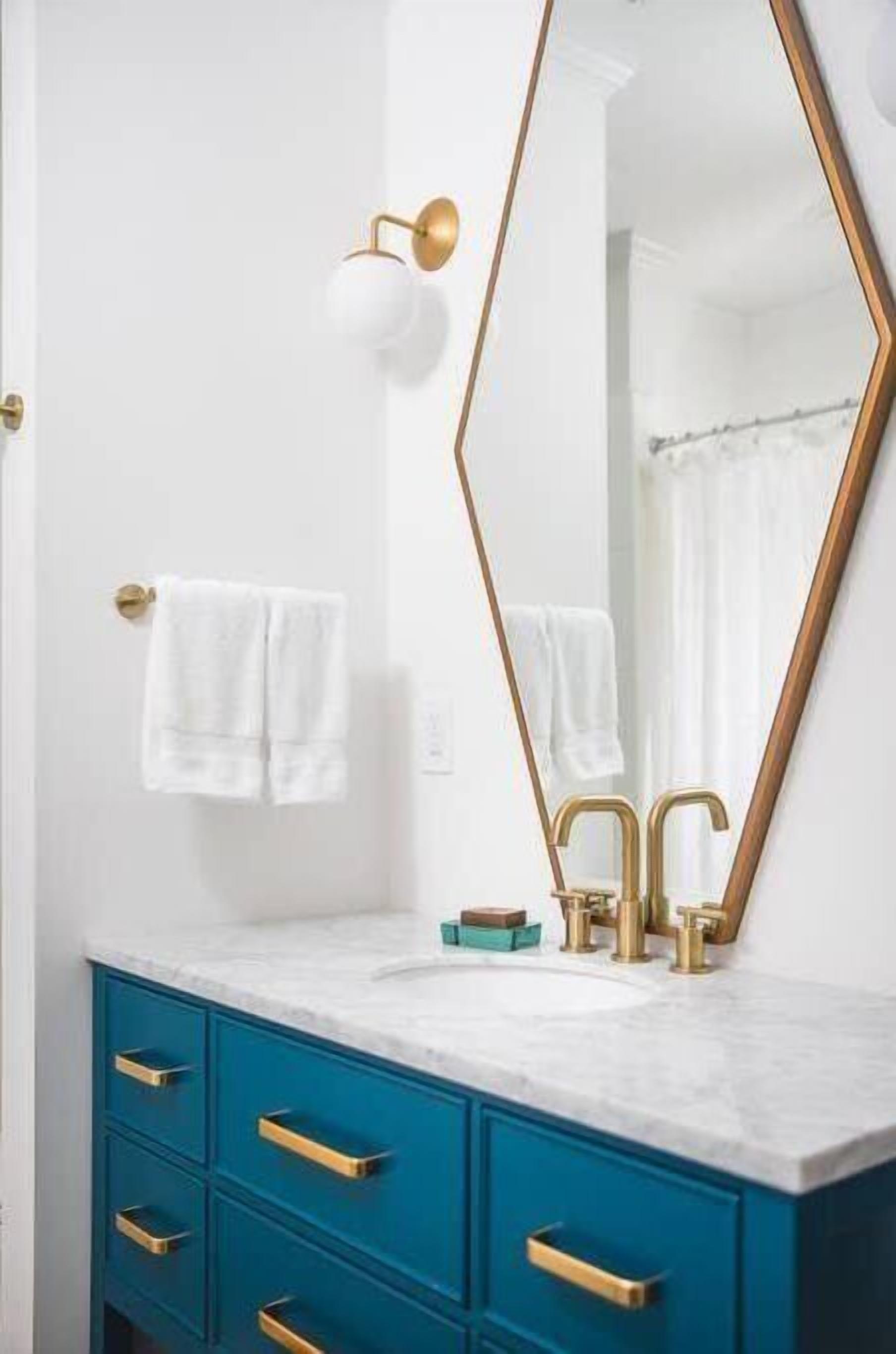 Une salle de bain avec un meuble-lavabo blanc, des robinets dorés et un grand miroir avec un cadre doré.