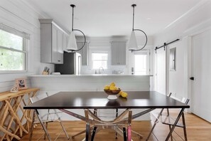 Une cuisine moderne avec des meubles blancs, une table en bois foncé et un saladier rempli de citrons.