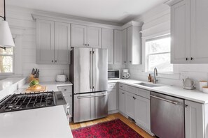 Una cocina moderna con armarios blancos, electrodomésticos de acero inoxidable y una alfombra roja.