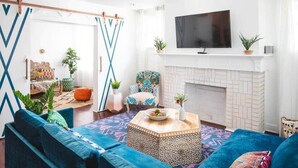 A living room with a blue sofa, a patterned coffee table, and a fireplace.