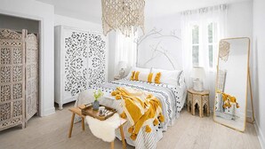 A bedroom with a bed, a bedside table, a hanging light fixture, and a mirror.