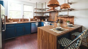 A modern kitchen with blue cabinets, a wooden island, and pendant lighting.