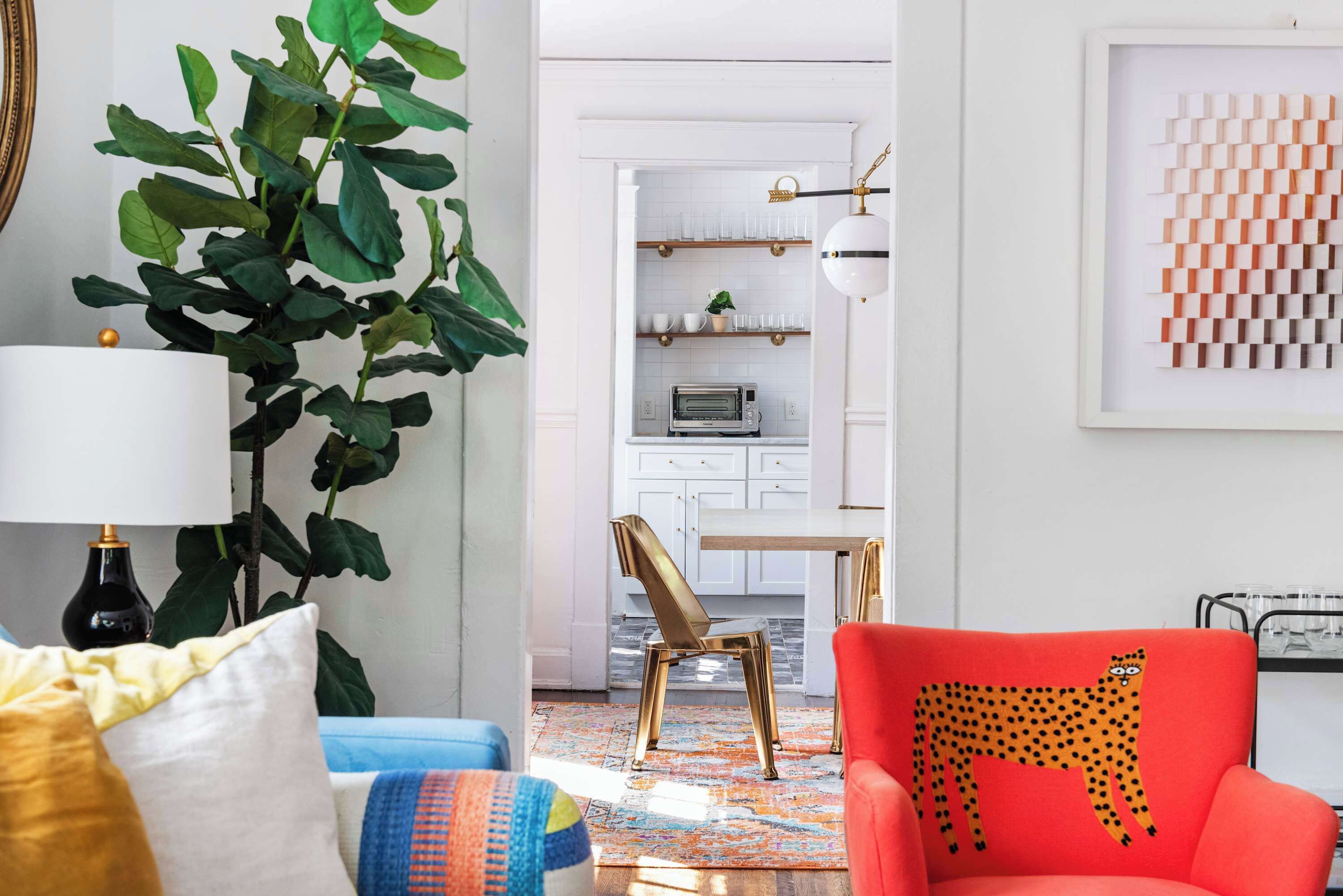 Una sala moderna con un sofá, un sillón, una lámpara y una planta grande.