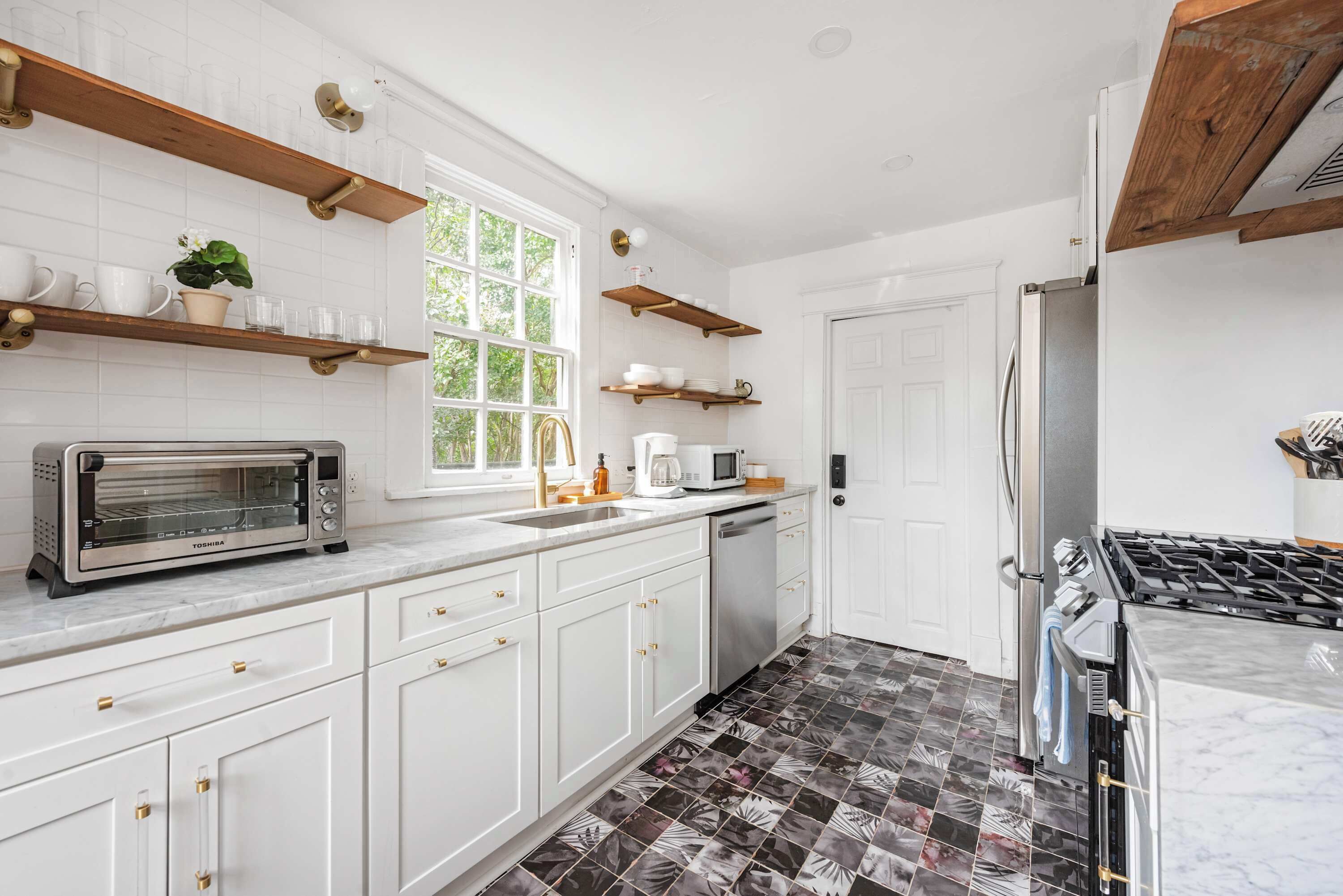 A modern kitchen with white cabinets, a built-in oven, a microwave, and a stainless steel refrigerator.