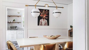 A dining area with a white table, gold chairs, and a hanging light fixture. - Lucky Leopard (Atlanta)