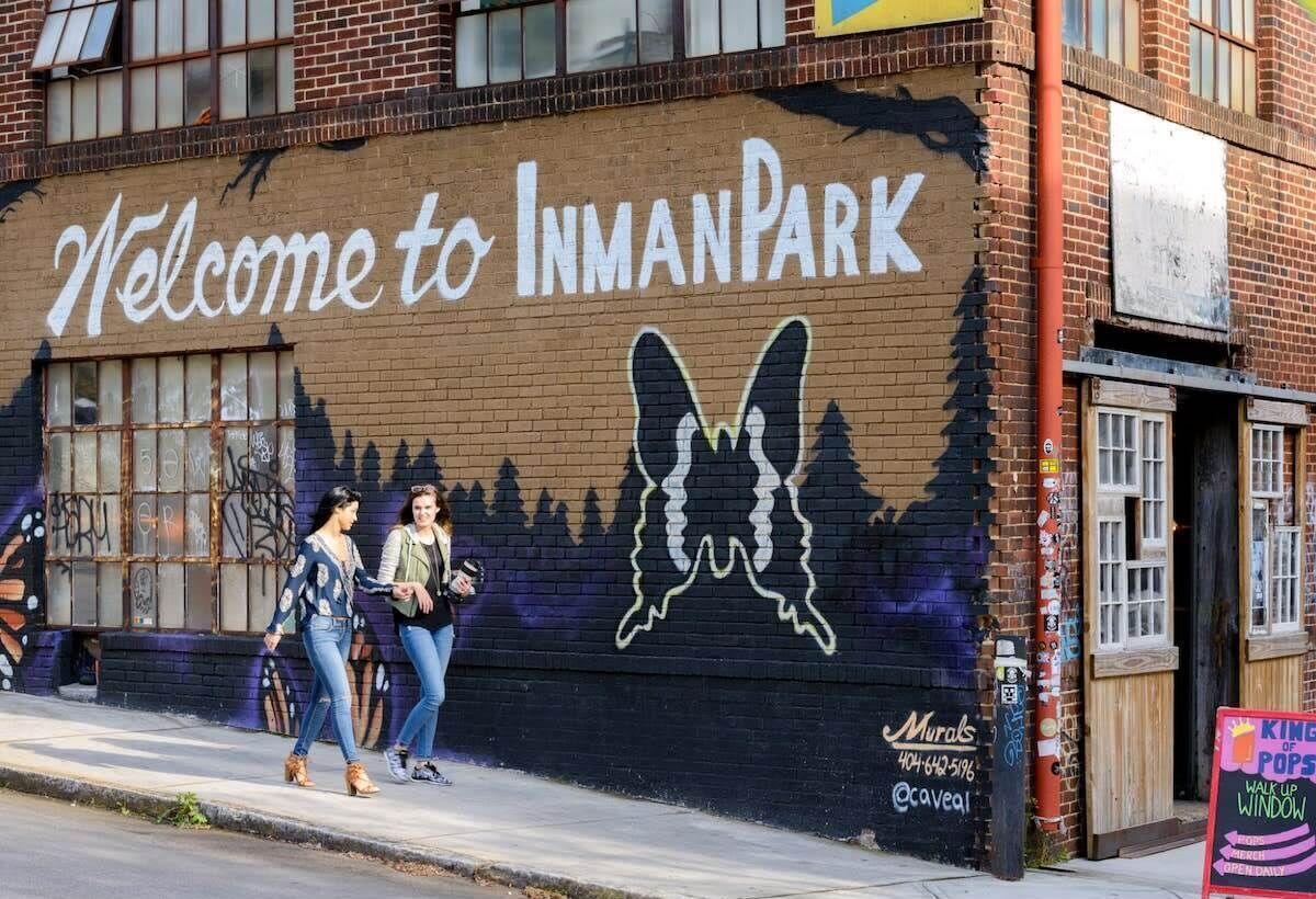 Een muurschildering op een gevel met de tekst "Welcome to Inman Park" en een silhouet van een vlinder.