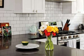 A kitchen with white cabinets, a stove, and a vase with flowers on the counter.