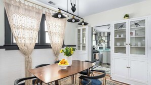 A dining area with a wooden table, black chairs, and a vase of yellow flowers.