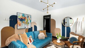 A modern living room with a blue sofa, a round coffee table, and a decorative mirror.