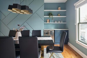 Un comedor moderno con una mesa negra, sillas a juego y una lámpara colgante de diseño geométrico.