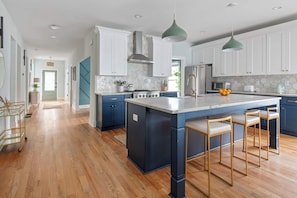 A modern kitchen with a central island, bar stools, and pendant lighting.