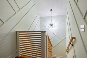 Una escalera con barandas de madera y una lámpara colgante.