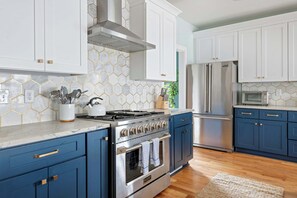 A modern kitchen with white cabinets, a stainless steel stove, and a blue countertop.