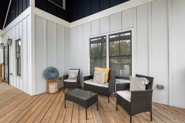 Un espacio de estar al aire libre cubierto con mobiliario de mimbre y una terraza de madera.