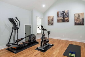 A home gym with two treadmills, an elliptical, and a stationary bike, along with exercise mats and dumbbells.