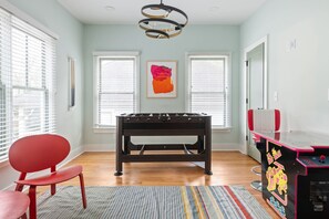 Quarto com mesa de futebol de campeonato, uma cadeira vermelha e uma mesa de futebol com design rosa e preto.