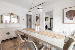 A modern dining area with a long table, chairs, and a decorative centerpiece.