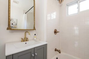 A bathroom with a white sink, a gold-framed mirror, and a bathtub.