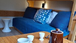 A cozy room with a bed, a wooden table with cups and a coffee pot, and a small white stool. - Studio in Center for 2, Free Wifi (Les Arcs 1800)