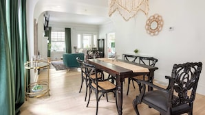 A dining area with a wooden table and chairs, a gold-framed serving cart, and a macramé wall hanging.
