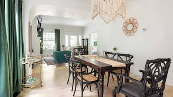 A dining area with a wooden table and chairs, a gold-framed serving cart, and a macramé wall hanging.