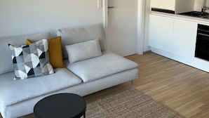 A modern living room with a grey sofa, a black coffee table, and a patterned throw pillow. - Terrace Flair (Wien)