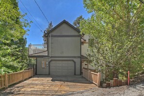 A two-story building with a large garage door, surrounded by a wooden deck and a white fence.