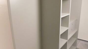 Ein begehbarer Kleiderschrank mit offenen Regalen und einer Kleiderstange aus Holz.