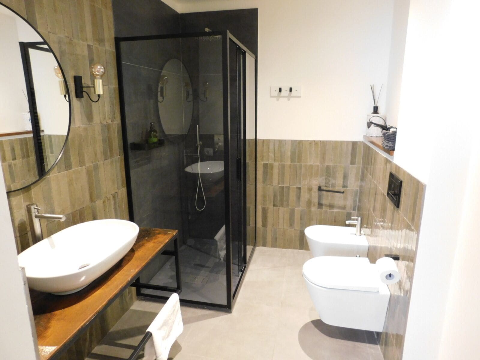 A modern bathroom with a glass-enclosed shower, a wooden vanity, a white sink, and a toilet.