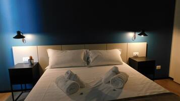 A hotel room with a neatly made bed, two bedside tables with lamps, and a blue accent wall.