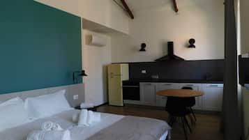 Een hotelkamer met een bed, een kleine kitchenette, een eettafel en een plafond met zichtbare balken.