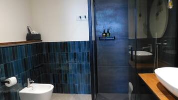 Een moderne badkamer met een bidet, een douchecabine met glazen wanden en een houten wastafelmeubel.