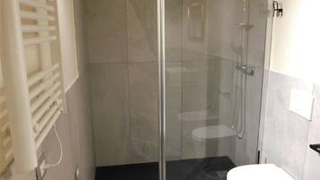 A modern bathroom with a glass-enclosed shower, a white toilet, and a bathtub.