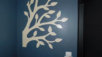 A wall with a white tree decal and a door with a control panel.