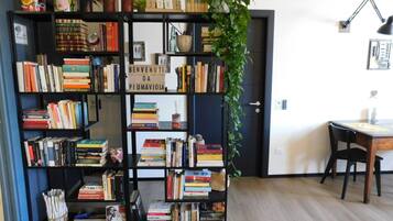Ein Zimmer mit Bücherregal, Schreibtisch, Stuhl und einer Zimmerpflanze.