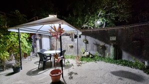 An outdoor patio with a table and chairs under a canopy, surrounded by potted plants and a concrete wall. - Sunset Beach View (Dhangethi)