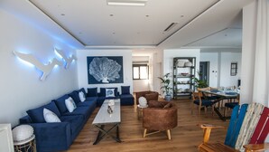 Una sala moderna con un sofá azul, una mesa de centro de madera y un comedor con mesa y sillas de madera.