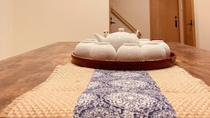 A hallway with a wooden floor, a patterned rug, a white teapot set, and a small framed picture on the wall. - Shirakawa Seiryuan Bettei (Kyoto)