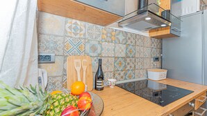 Una cocina con mostrador de madera, un bol de vidrio con fruta, una botella de vino y una taza de café.